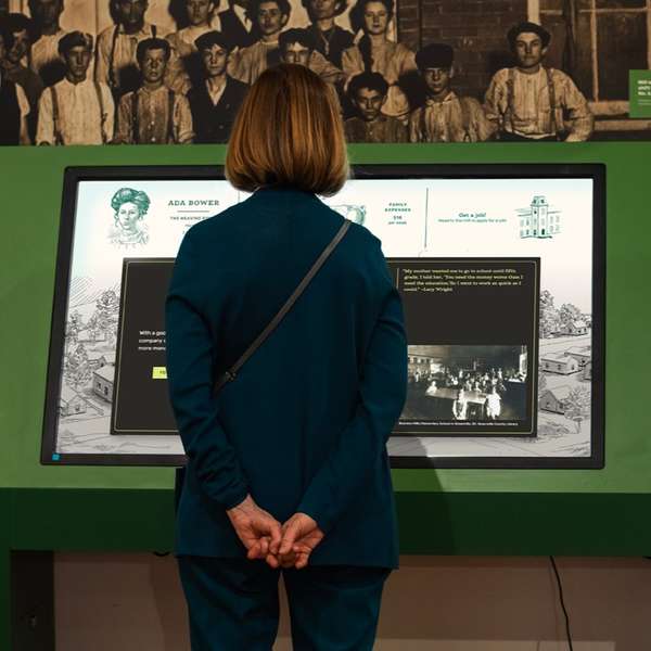 A woman standing in front of a touchscreen in a gallery.