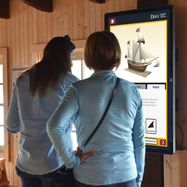 Two women looking at the interactive on a large wall tablet