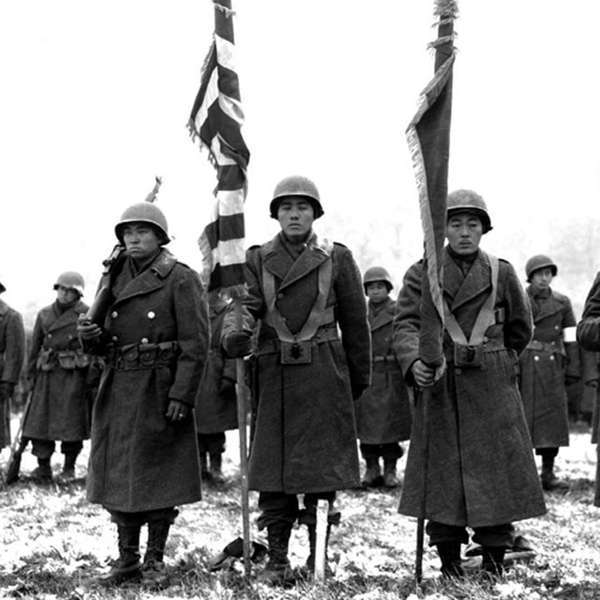 A historic photo of a group of soldiers standing with a flag