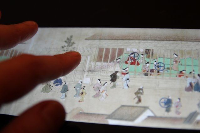 A person is pointing at an image of a Chinese painting on a tablet.