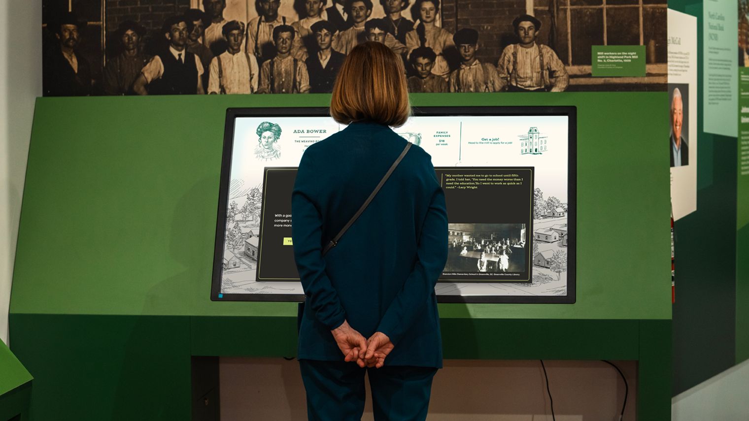 A woman standing in front of a touchscreen in a gallery.