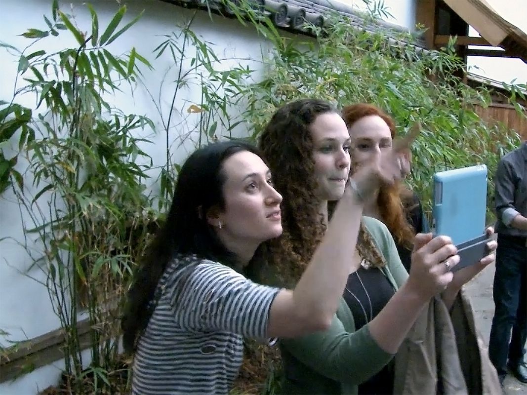 A group of people holding up a tablet.