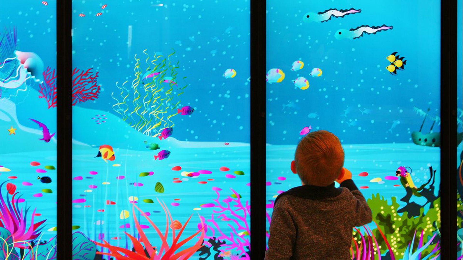 A child looking at the interactive on a wall tablet